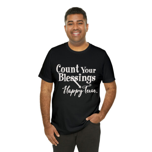 A man wearing a black t-shirt with the words " count your blessings and happy times ".