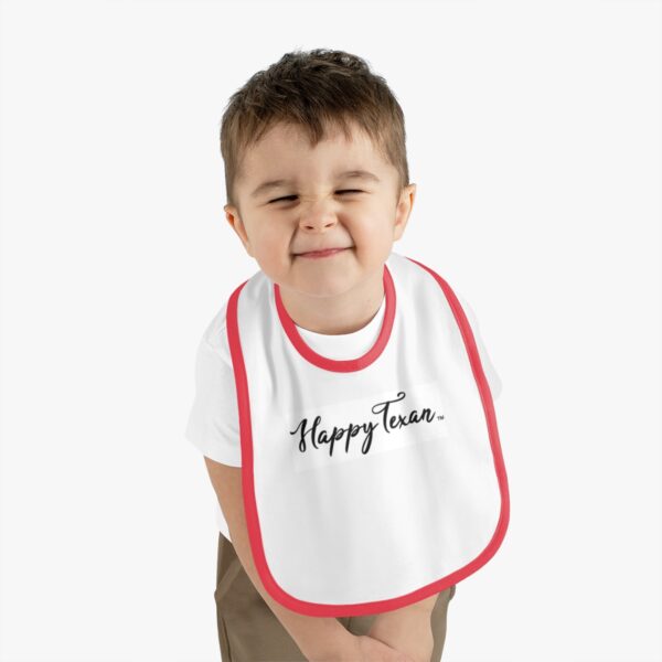 A young boy wearing a bib with the words " happy tears ".