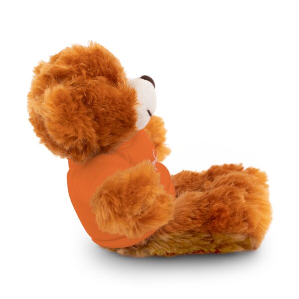 A teddy bear in an orange shirt sitting down.