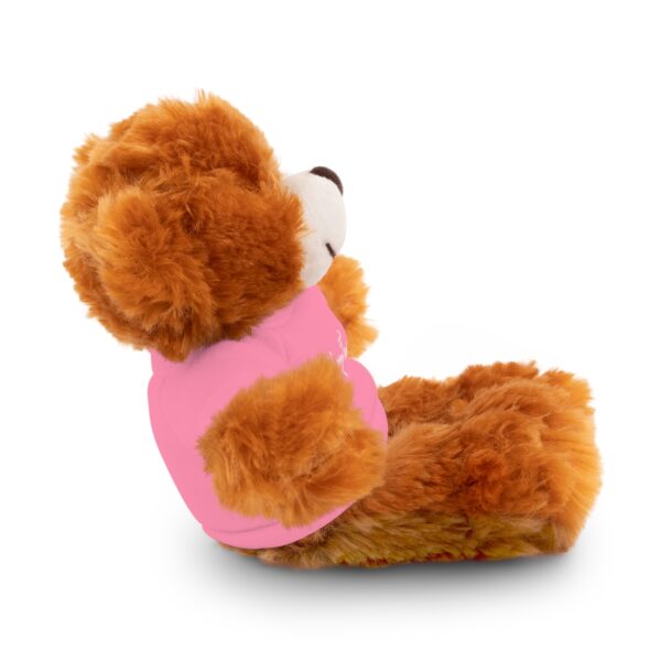 A teddy bear sitting in a pink shirt.